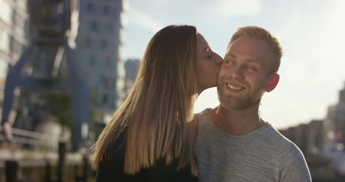 Cool young woman is giving her boyfriend a tender kiss on the cheek