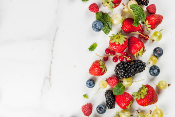 Summer fruit and berries. 6 types of raw organic farmer berries - raspberries blackberries blueberries strawberries red currants gooseberries. On white marble table. Copy space top view