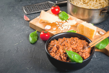 Ingredients of Italian cuisine. Products for the preparation of pasta bolognese, the cooking process. Welded spaghetti in pan, bolognese sauce, basil, garlic, tomato, parmesan Copy space