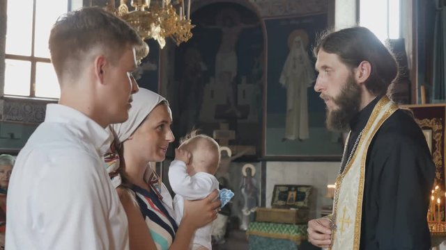 The mother kisses a cross during the ritual of baptizing of her son in church