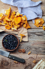 Forest harvest: blueberry and chanterelle mushrooms on gray rustic background with a piece of linen cloth. Autumn nature concept. Top view with copy space centered.