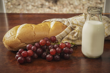 bottle of milk with fresh loaf of bread and red grapes