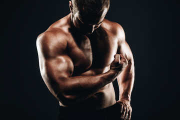 Close up Strong athletic bodybuilder with muscular arm, perfect abs, shoulders, biceps, and triceps  chest, personal fitness trainer flexing his muscles