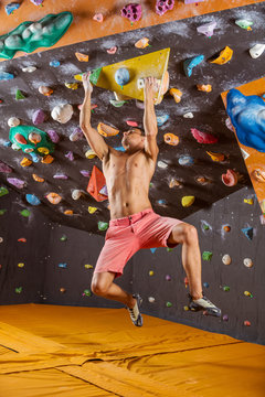 Young man bouldering in indoor climbing gym