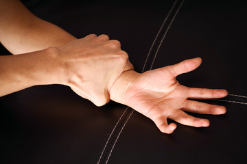 Close up man's hand holding a woman wrist over a black coach for rape and sexual abuse concept