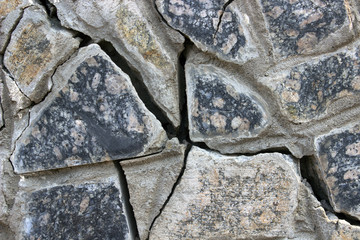 Large cracks in a broken stone wall