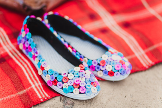 Black flat shoes made from textile covered with colored buttons.