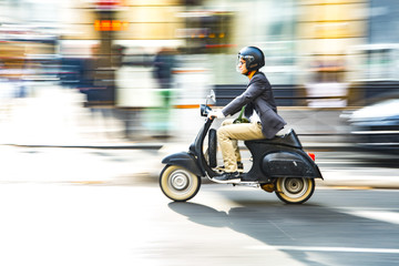 Fototapeta na wymiar A man is riding a moped along the street