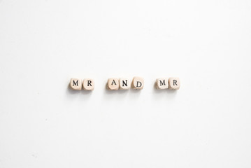 Rustic wooden alphabet blocks spelling MR AND MR on white background from above - marriage equality concept