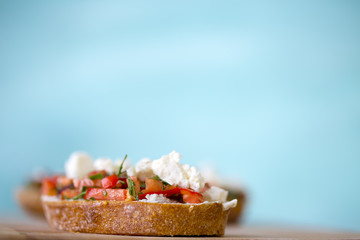 Bruschetta with tomato, cheese and olive oil on a blue background