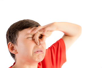 Young teenage boy isolated on a white background holding his nose