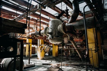 Foto auf Alu-Dibond Metal rusty equipment, large industrial pipes in abandoned factory in workshop room © DedMityay
