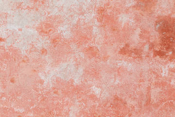 Close-up of a weathered and aged concrete wall, bleached red paint partly peeled off. Texture background.