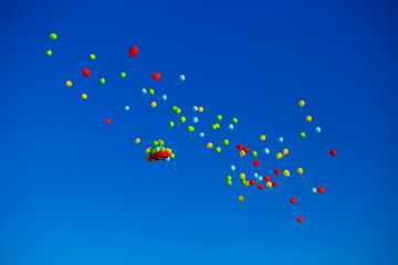 Group of multicolored helium filled balloons in the blue sky