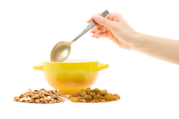 Porridge in a plate with a spoon in a female hand raisins nuts