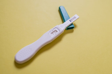 Positive White Plastic Pregnancy Test Isolated on yellow Background.