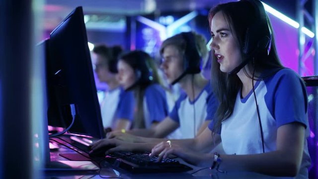 Beautiful Professional Gamer Girl and Her Team Participate in eSport Cyber Games Tournament. She Has Her Headphones and as a Team Leader She Commands Strategical Maneuvers into Microphone.