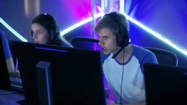 Moving Shot of Team of Boys and Girls Gamers Playing in Multiplayer PC Video Game on a eSport Tournament.  Shot on RED EPIC-W 8K Helium Cinema Camera.