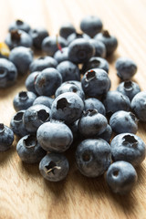 Ripe strewn blueberries on a wooden table, vertically.