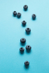 Ripe spilled blueberries on a blue background, vertically.