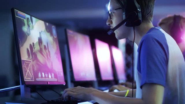 Team of Professional eSport Gamers Playing in Competitive  MMORPG/ Strategy Video Game on a Cyber Games Tournament. They Talk to Each other into Microphones. Arena Looks Cool with Neon Lights. 