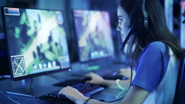 Professional Girl Gamer Plays in MMORPG/ Strategy Video Game on Her Computer. She's Participating in Online Cyber Games Tournament, Plays at Home, or in Internet Cafe. 
