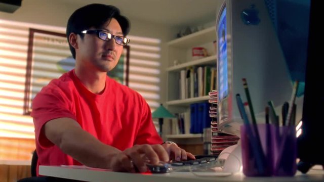 Asian man types on computer. 