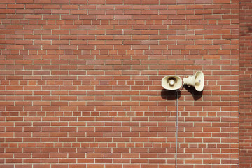 Red brick wall of a residential building and two loudspeakers.