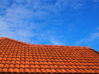 Orange cement tile ladder step like roof, with blue sky and fade distributed white cloud background