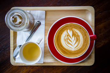 aroma coffee red cup latte art and tasty cake on wood table in coffee shop with vintage dark tone and copy space