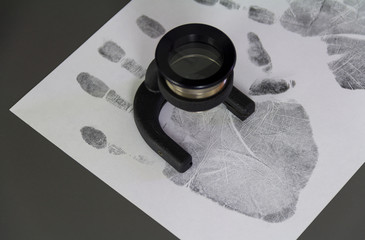 Fototapeta premium The investigation of the crime. A fingerprint on a paper with a magnifying glass