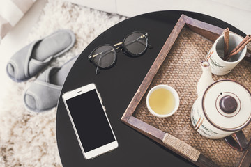 cup of tea on wooden tray on a round table with sofa in living room