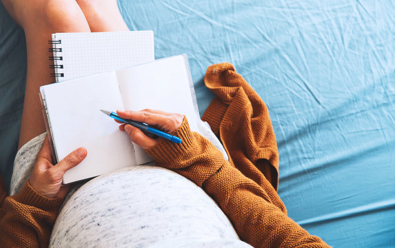 Pregnant woman makes notes and looking at medical documents.