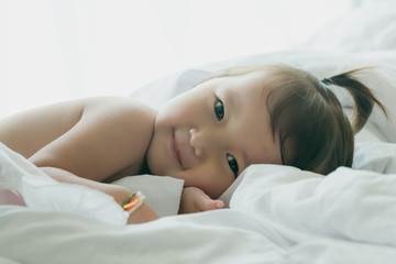 Obraz na płótnie Canvas child lying smile in white bedding room for copy space :soft focused