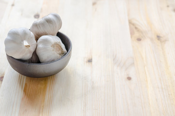 Garlic in black bowl on wooden table background