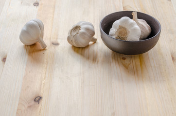 Garlic in black bowl on wooden table background