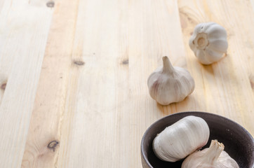 Garlic in black bowl on wooden table background