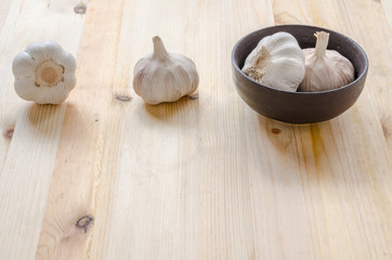 Garlic in black bowl on wooden table background