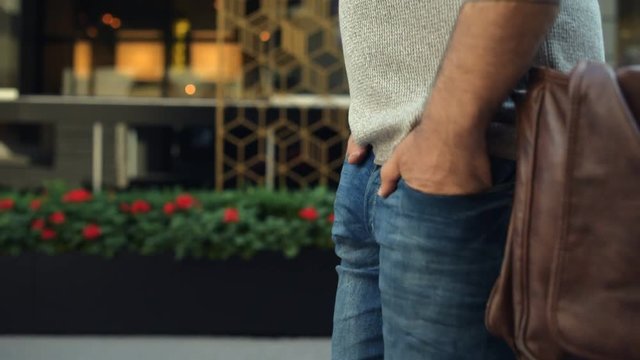 Close up of man walking with hands in pockets