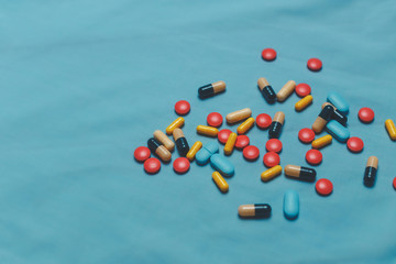 Different Colorful Pills, Tablets And Capsules On Blue Background