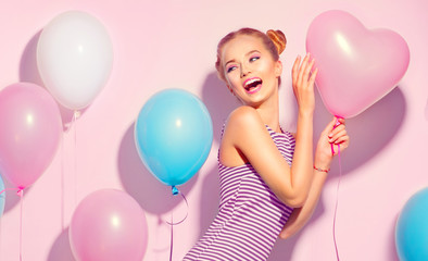 Beauty joyful teenage girl with colorful air balloons having fun over pink background