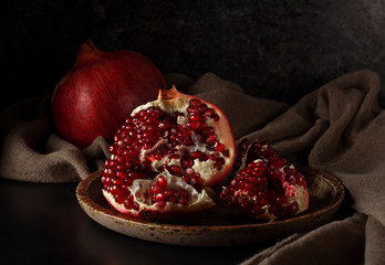 Still life with red juicy pomegranates over dark background. Organic Bio fruits