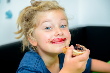 funny girl eating bread roll with marmelade