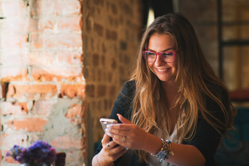 A girl is sitting in a cafe and looking into the phone