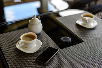 Coffee and telephone on the table of a summer cafe