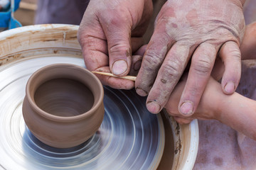 Fototapeta na wymiar A child makes a clay pot on a potter's wheel