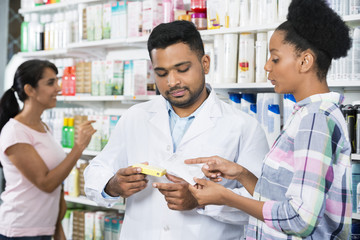 Customer And Chemist With Prescription In Pharmacy