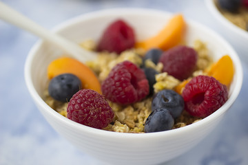 Bowls of  granola  with  fresh fruit on marble table.