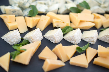 Different types of cheeses on black board.