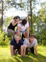 Fototapeta premium Happy Coworkers Making Human Pyramid On Grassy Field